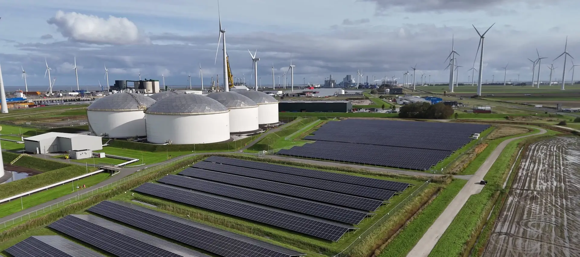 Zonnepark met batterijopslag en windturbines op de achtergrond
